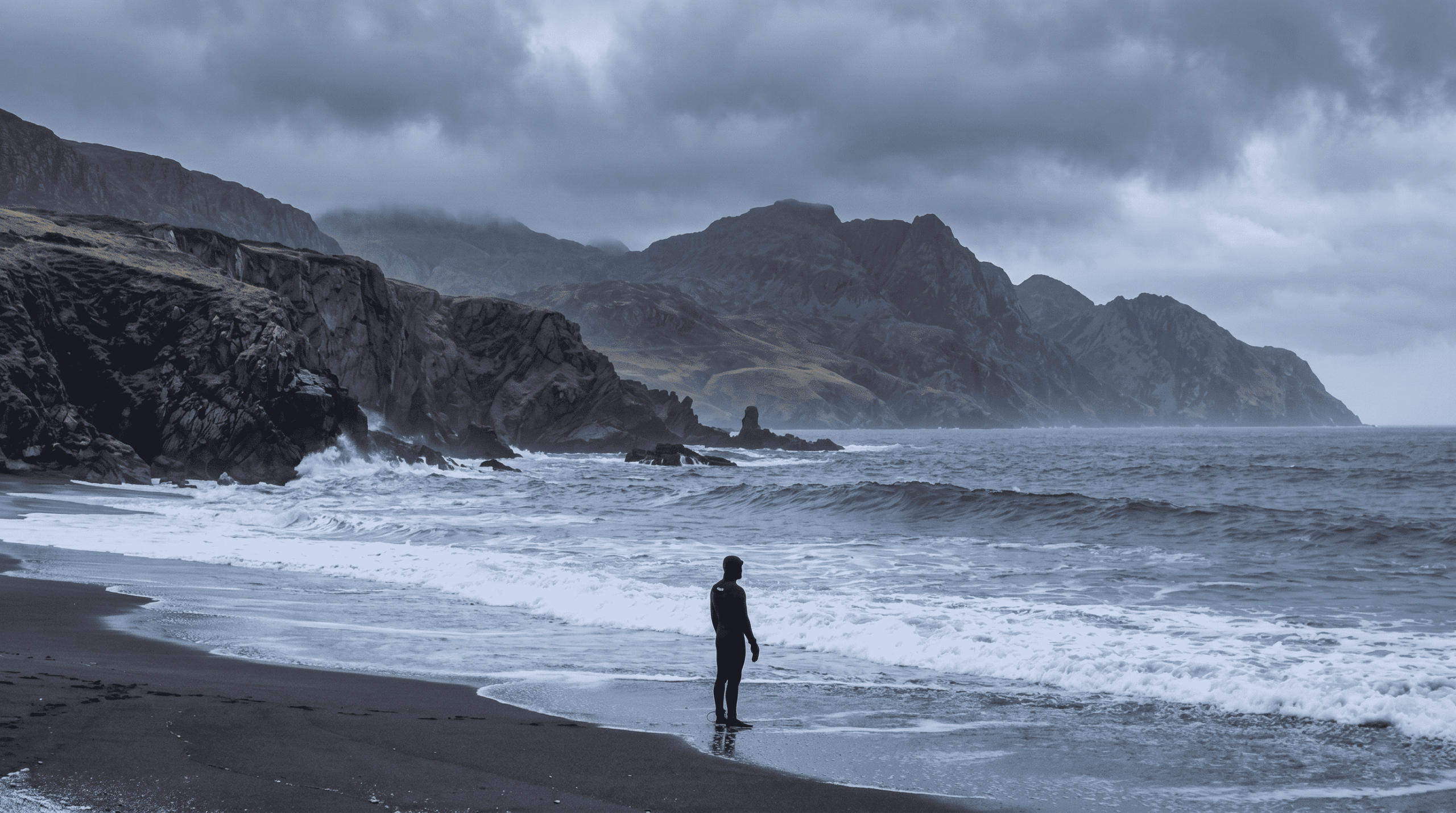 Surfer analysing waves, his is usign a wetsuir for cold water