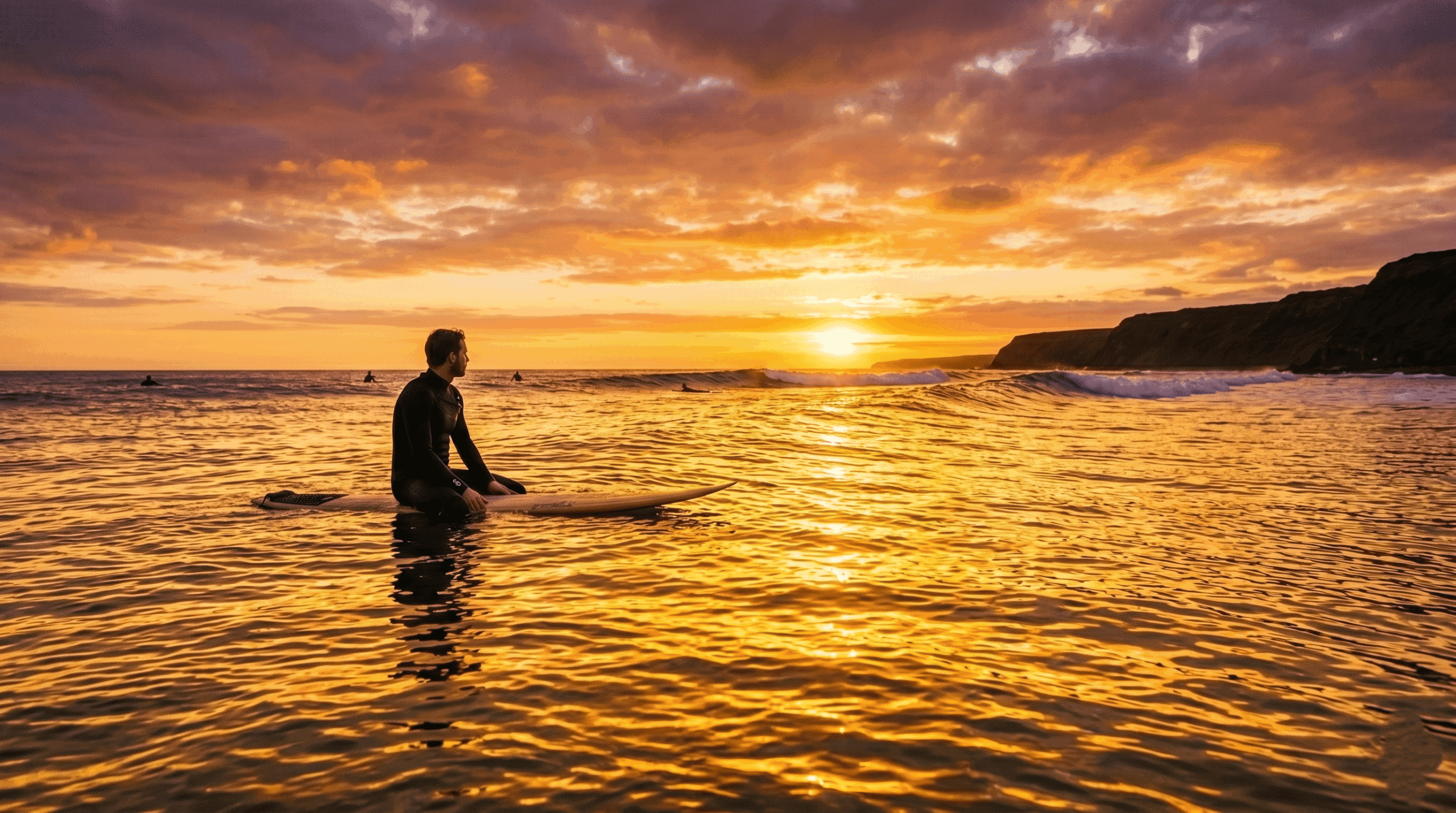 Surfer sitting on his board in the lineup during sunset.